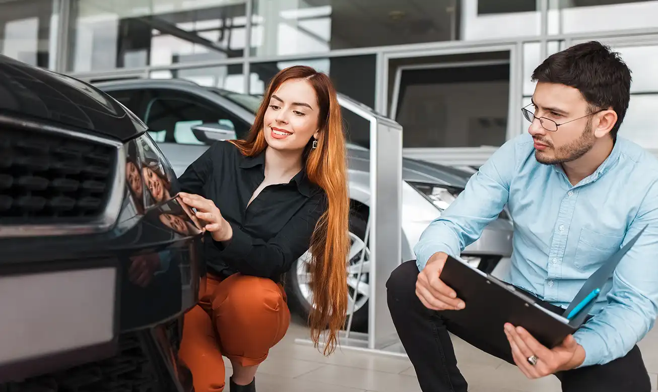 Vendedor revisa junto a la clienta los detalles del coche